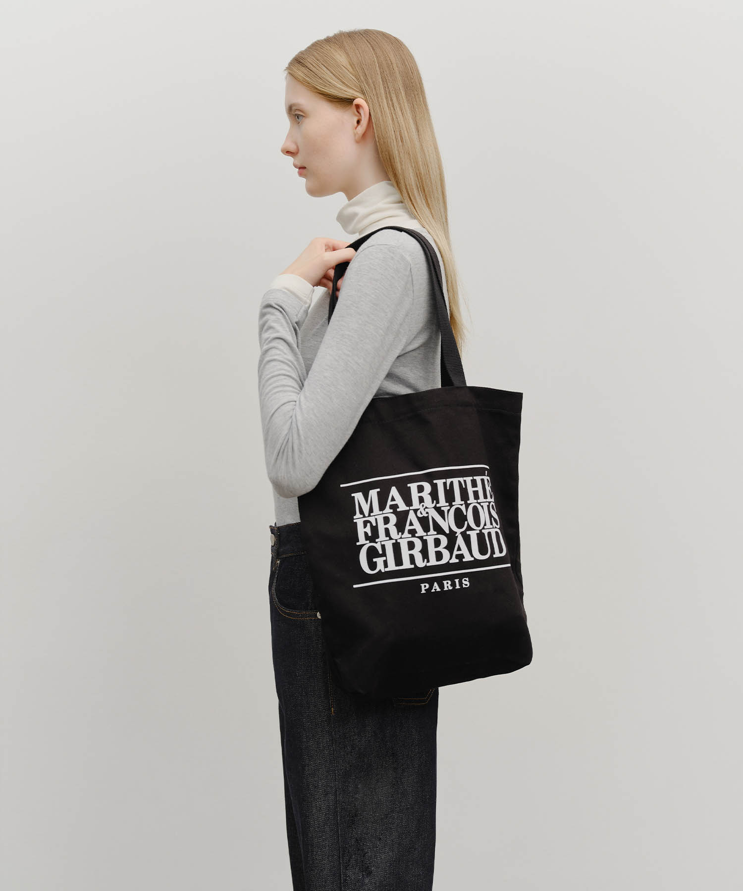 Marithé Classic Logo Eco Bag in black worn over the shoulder, side view